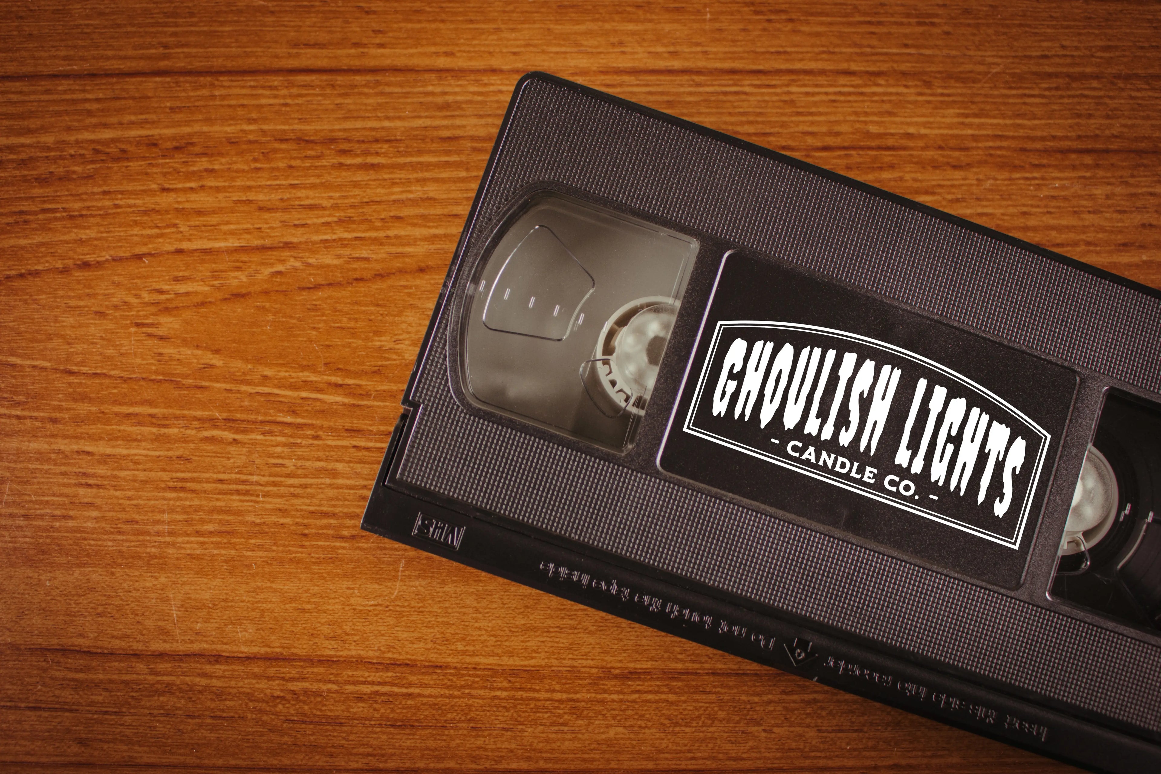 Videokassette mit Logo von Ghoulish Lights Candle Co. auf Nussbaumholz-Hintergrund